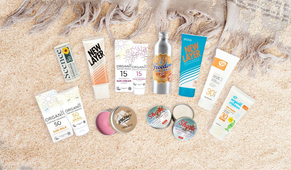A selection of nature-friendly sunscreens laid out on a sandy background with a beach towel 